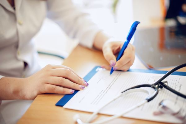 Farmacia de especialidades; médico escribiendo con un estetoscopio azul