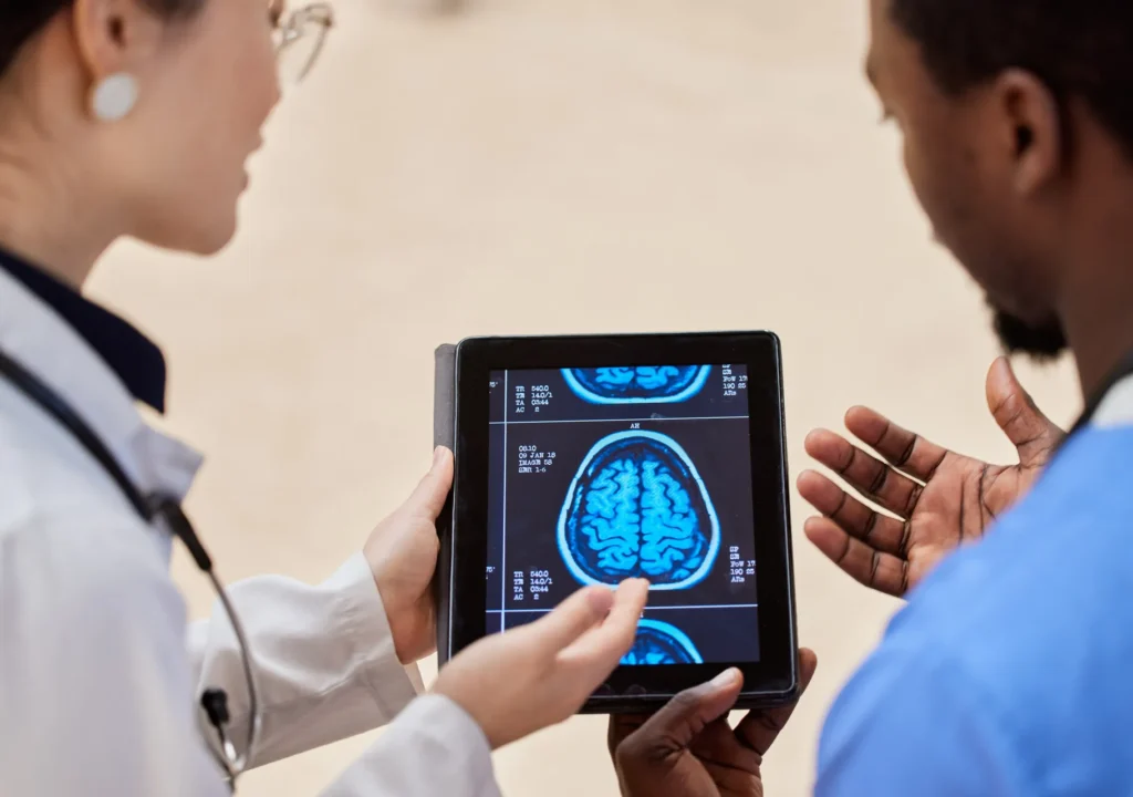 Fotografía de dos doctoras de espaldas revisando en una tablet una placa neurológica mientras analizan información sobre madopar para qué sirve