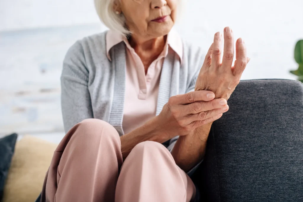 acercamiento a las manos de una mujer mayor con artritis que se soba una mano con la otra y usa deflazacort para qué sirve en el alivio de inflamación y dolor articular