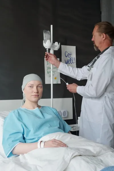 Una paciente en una cama de hospital recibiendo una infusión de busulfán mientras un médico ajusta el equipo.